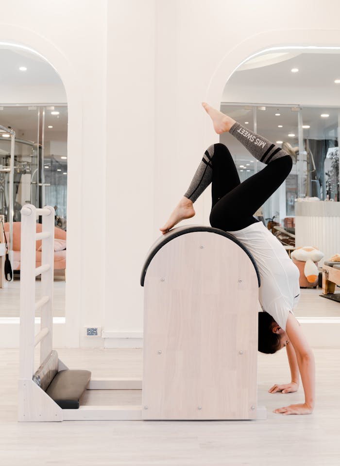 Woman engaging in a Pilates exercise with stretching equipment in a modern gym setting.